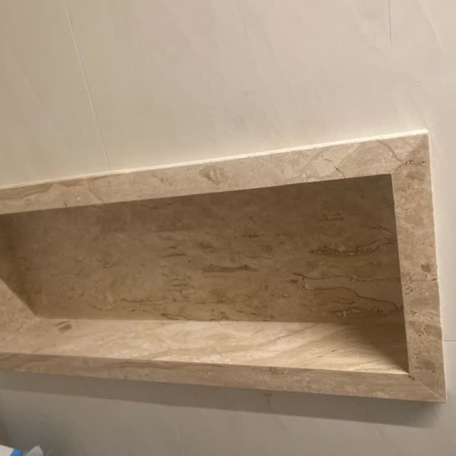Nicho de box em mármore: Nicho embutido no box, todo em mármore bege com veio horizontal, com as quatro faces em peça contínua.