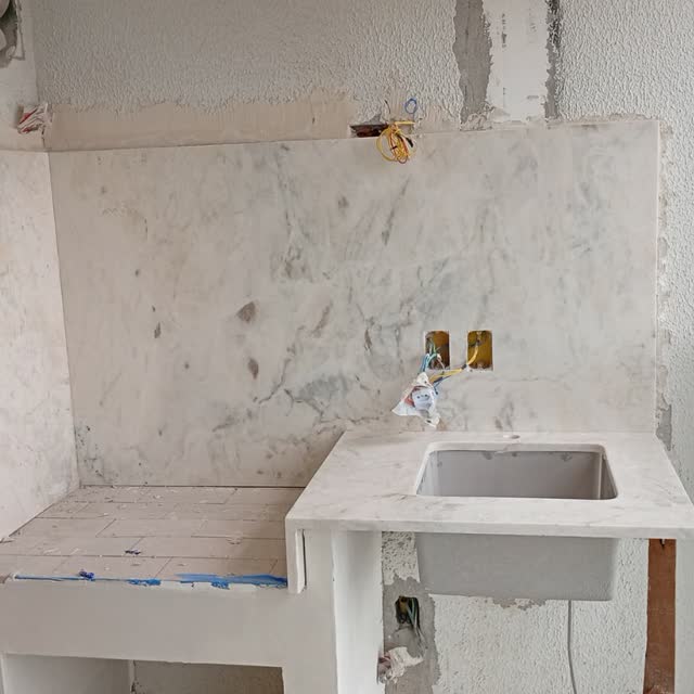 Bancada de banheiro em obra: Bancada em mármore claro com cuba esculpida, instalada antes do acabamento da alvenaria.