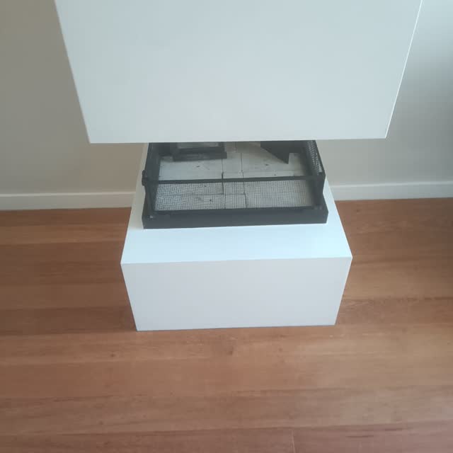 Bancada com cooktop: Bancada branca em peça única com recorte de cooktop e apoio central, sobre piso de madeira.
