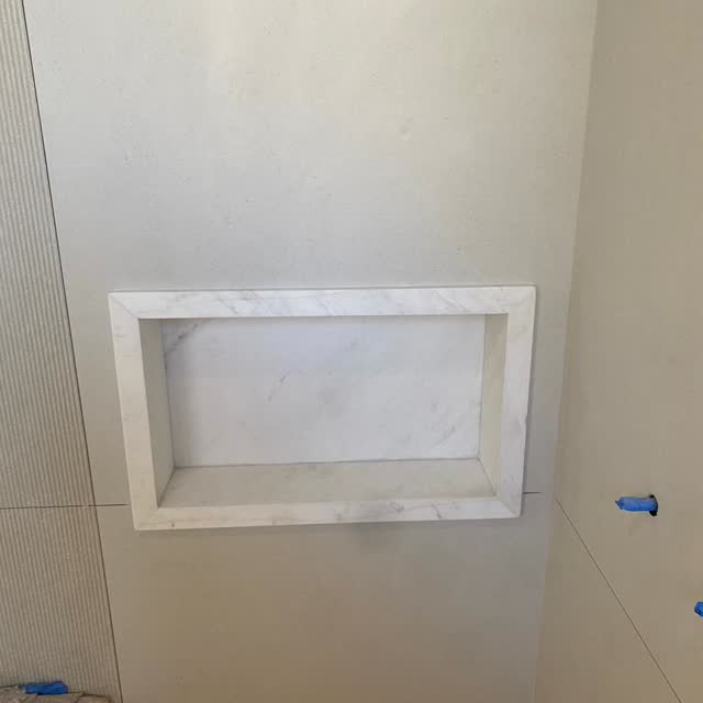 Nicho em mármore branco: Nicho de box em mármore branco, com moldura em peça contínua e junta seca nos encontros.
