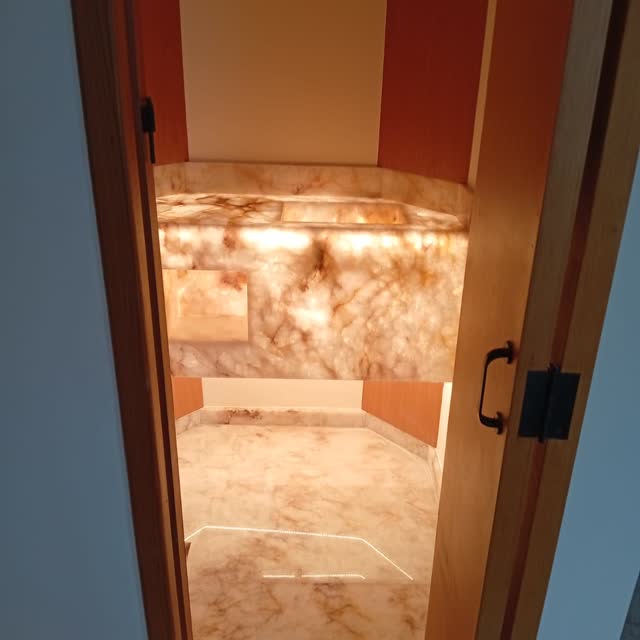 Lavabo em ônix retroiluminado: Lavabo inteiro revestido em ônix com iluminação por trás da pedra — parede, bancada e cuba no mesmo material.