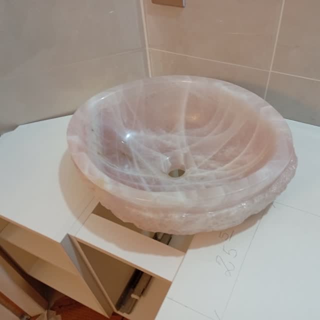 Cuba esculpida em quartzo rosa: Cuba escavada em bloco maciço de quartzo rosa, com a borda acompanhando o veio natural da pedra.