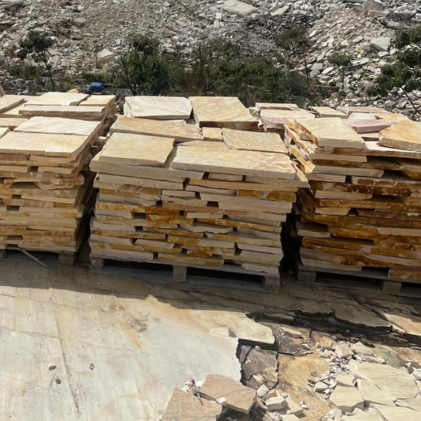 Paletes de pedra amarela empilhados, prontos para carregar.