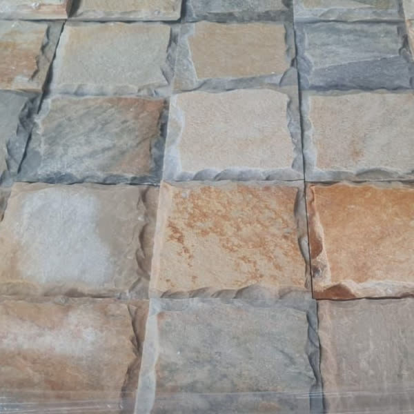 Placas quadradas rústicas mescladas, em tons de ferrugem, creme e cinza, embaladas em palete.
